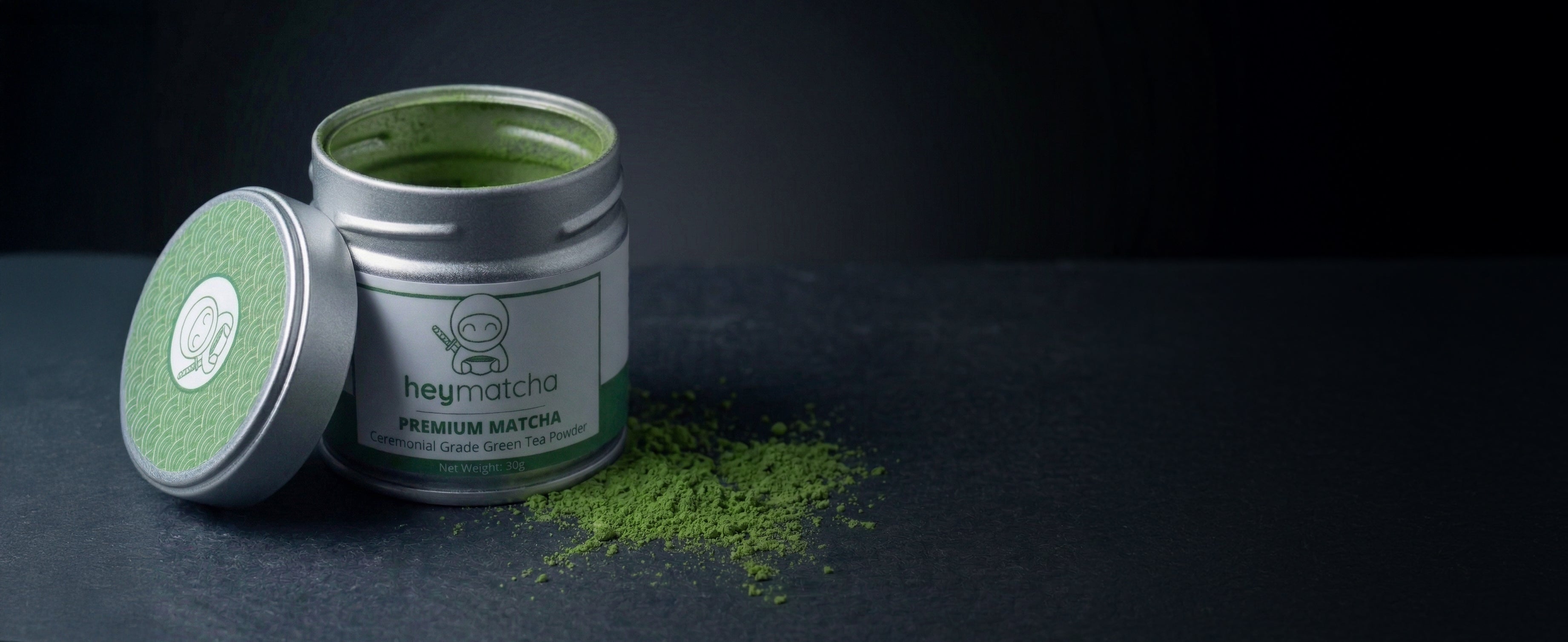 Silver canister of matcha green tea powder with a black background